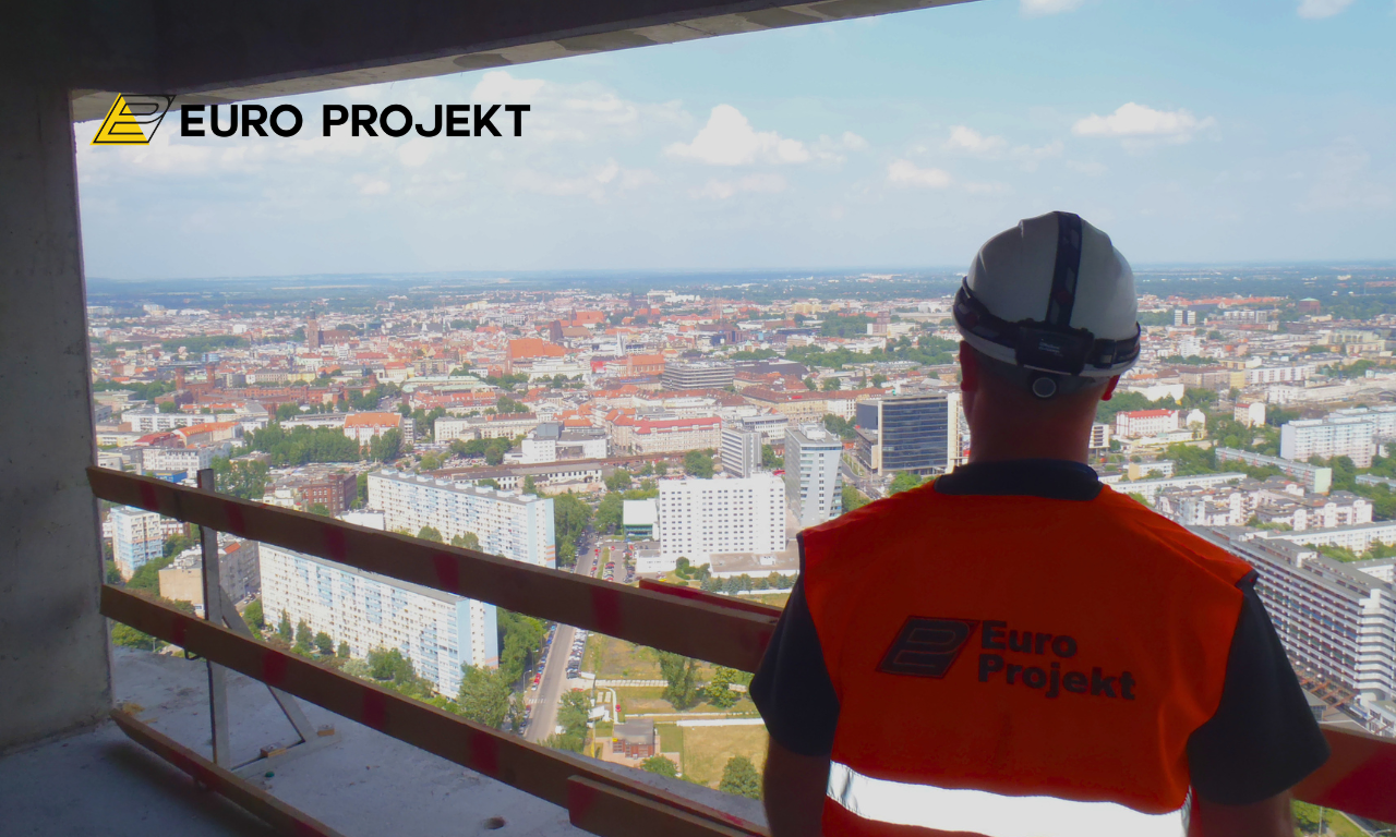 Pracownik na wysokości przy wieżowcu Sky Tower, w tle panorama Wrocławia